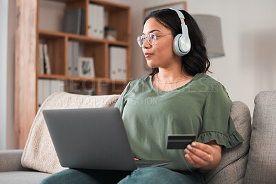 Buy stock photo Woman, laptop and credit card with headphones and online shopping on sofa, music subscription payment and fintech. Female customer at home, thinking of finance with e commerce and podcast membership