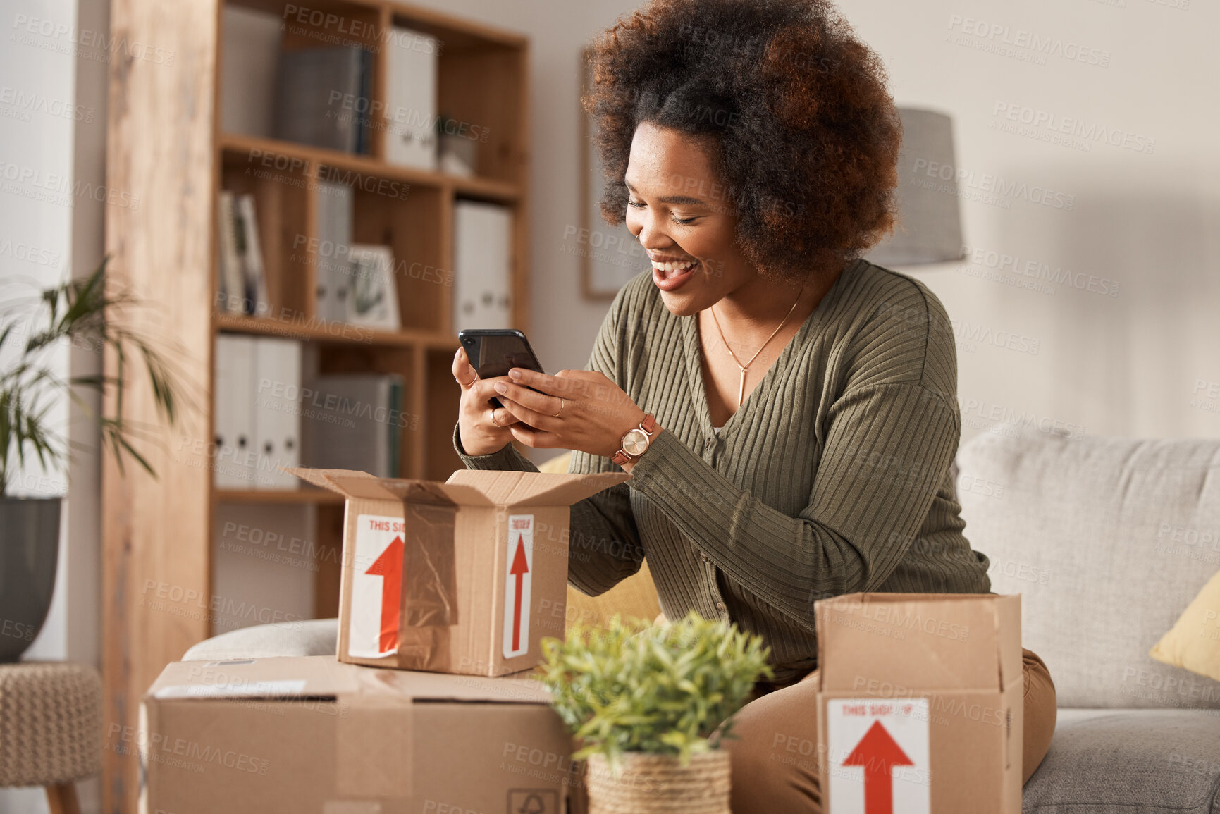 Buy stock photo Boxes, phone and woman unboxing for online shopping, courier service and product review on social media. Cardboard package, e commerce and happy african person or influencer on mobile at home on sofa