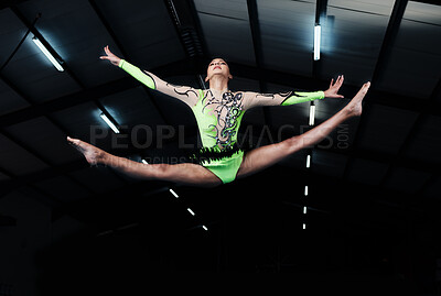 Woman, jump and gymnastics with fitness and competition, action and grace with performance in arena. Female gymnast in air, athlete exercise with flexibility and health for sports, flying and acrobat