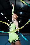 Happy, woman and rhythmic gymnastics with ribbon in gym, creativity and action, performance and fitness. Competition, athlete and female gymnast, dance and art with body, routine and energy at arena