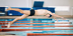 Sports, pool and male athlete diving for training, exercise or competition for indoor swimming. Fitness, action and young man swimmer doing a dive jump for a cardio workout or water sport gala.
