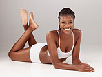 Portrait, fitness and body with a model black woman on a studio floor against a gray background for lifestyle. Beauty, skincare and smile with a happy young female person posing for wellness