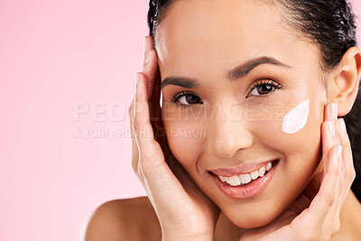 Buy stock photo Cream, beauty and face of a woman with skin care, dermatology and natural glow. Closeup of a young female model with a smile for moisturizer, cosmetic space or sunscreen on pink background in studio