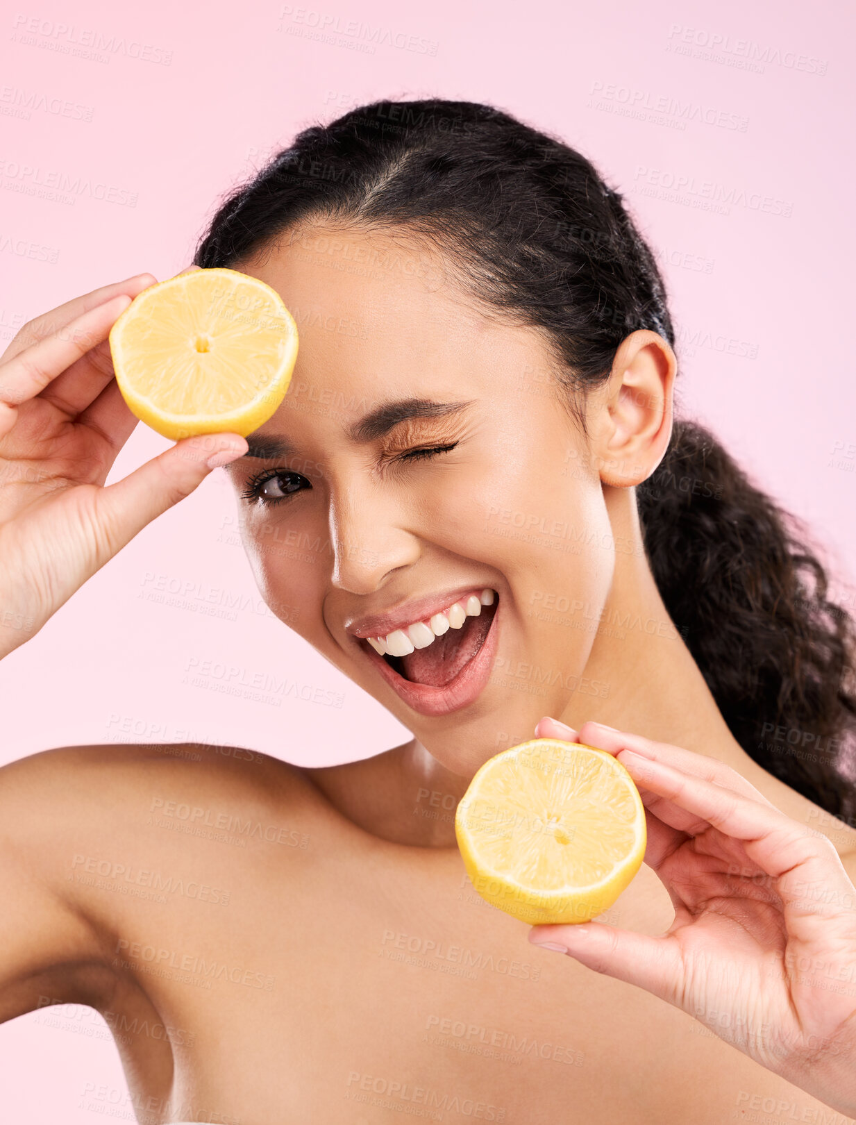 Buy stock photo Woman, beauty and lemon for wink in studio portrait, smile and natural skin glow by pink background. Latino girl, model and fruit for cosmetics, eye emoji and detox for wellness, nutrition and shine