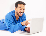 Surprise, laptop and man pointing on studio floor isolated on a white background. Computer, happy and person on ground for social media, streaming movie or film, video or show on internet with tech