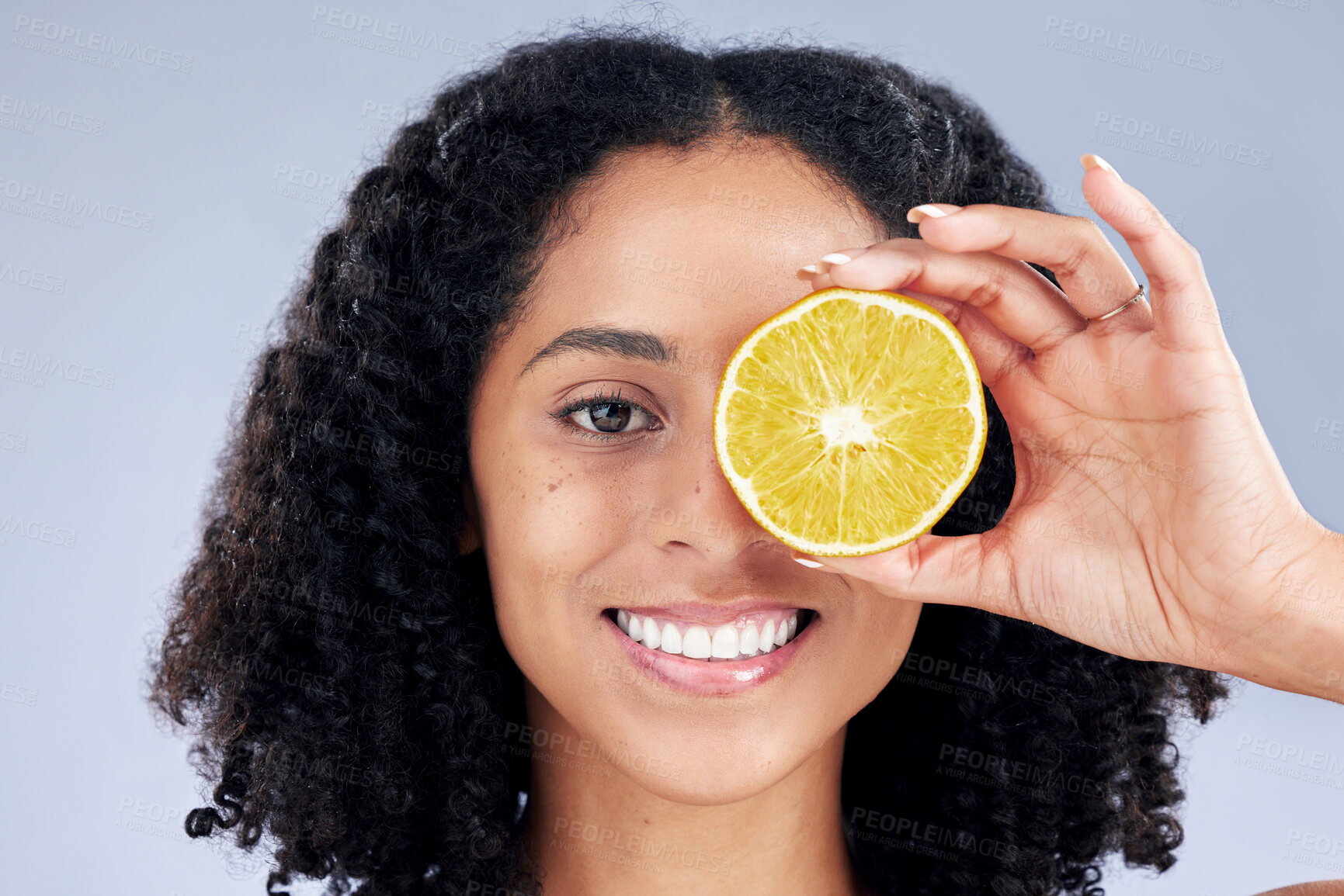 Buy stock photo Skincare, smile and lemon eye for nutrition or fruit with glow in grey studio background. Female person, portrait and vitamin c  or natural with facial treatment and organic food for dermatology.