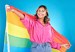 Lgbtq flag, portrait and woman with support, pride and happiness on a blue studio background. Female person, ally or model with symbol for queer community, equality or transgender rights with freedom