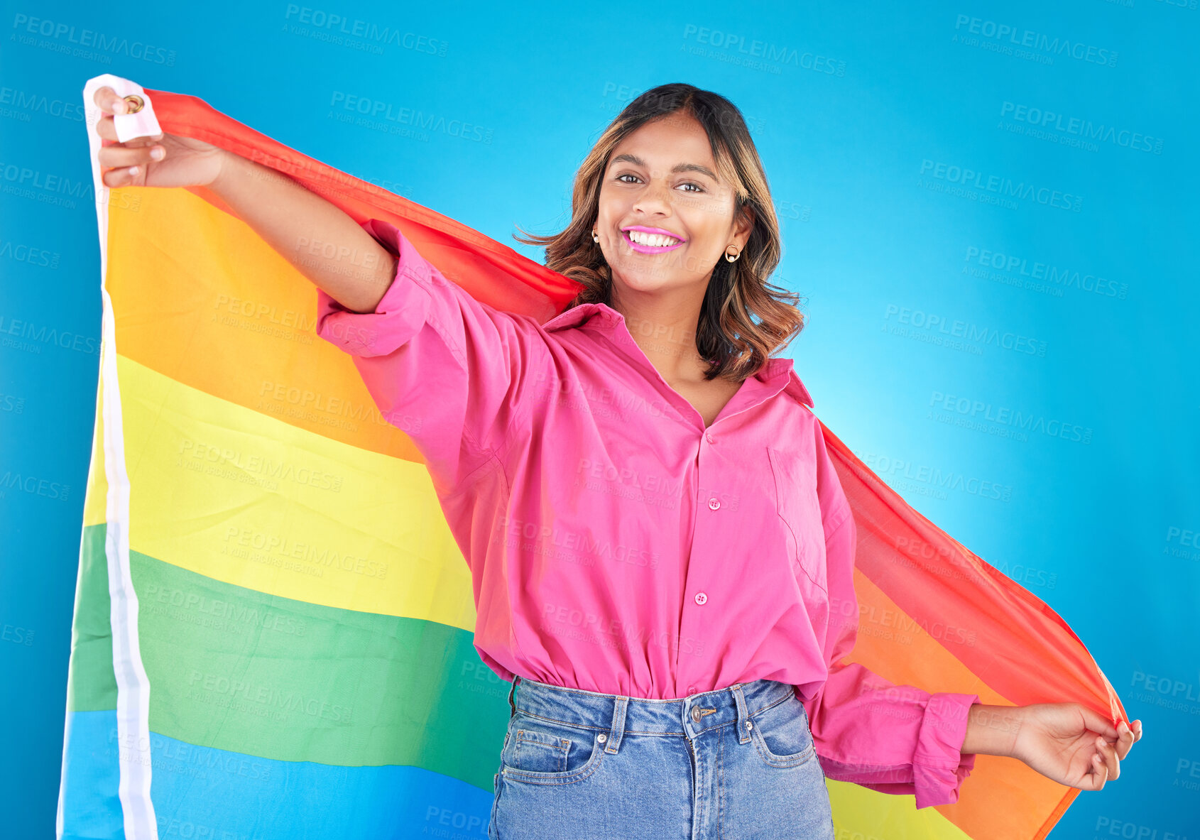 Buy stock photo Lgbtq flag, portrait and woman with support, pride and happiness on a blue studio background. Female person, ally or model with symbol for queer community, equality or transgender rights with freedom