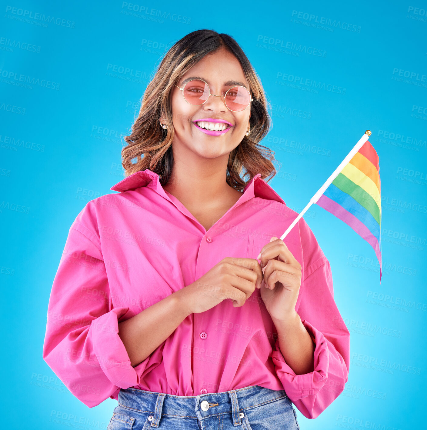Buy stock photo Woman, smile and pride flag in studio portrait with fashion, sunglasses and sign for human rights by blue background. Gen z girl, lesbian student and happy at protest, support and freedom for lgbtq