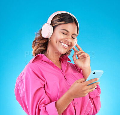 Buy stock photo Happy, woman and smartphone, headphones and music with audio streaming isolated on blue background. Entertainment, happiness and fun with female person listening to podcast or radio on mobile app