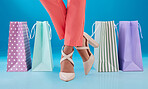 Feet, shopping bag and woman with sale, studio or fashion for discount, promo or deal by blue background. Shoes, style and girl for gift, choice or present for commerce, customer experience or retail