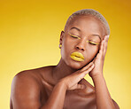 Face, creative makeup and lipstick with a black woman in studio on a yellow background for beauty or cosmetics. Gold, color and eyeshadow on young model with eyes closed for fashion or aesthetic