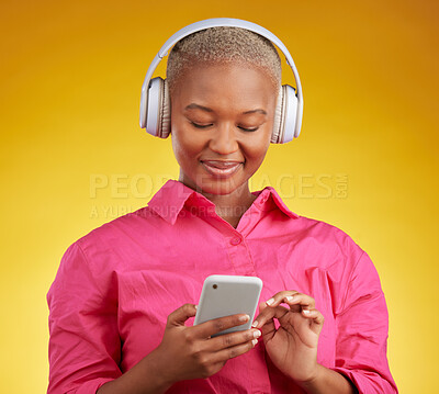 Buy stock photo Phone, smile and black woman with music headphones in studio for streaming, track or selection on yellow background. Radio, podcast and African female online with smartphone for audio subscription