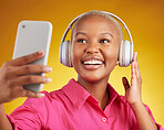 Selfie, smile and black woman with music headphones in studio, streaming or subscription on yellow background. Podcast, profile picture and lady social media influencer online for radio or blog post