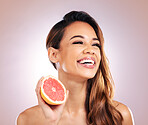 Happy woman, grapefruit and smile for vitamin C in skincare against a studio background. Face of female person or model with organic fruit for natural nutrition, diet or healthy wellness in happiness