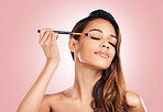 Makeup, eyeshadow and face of woman with brush on pink background for beauty, wellness and luxury. Cosmetology, aesthetic and female person with tools for foundation, cosmetics and glamour in studio