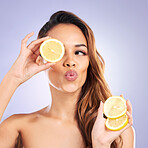 Citrus, lemon and eye of woman with beauty, natural or organic wellness isolated in a purple studio background. Excited, happy and healthy young female person with vitamin c for skincare or detox
