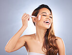 Happy woman, face roller and massage for skincare, rose quartz cosmetics or salon dermatology on studio background. Female model, crystal stone tools or smile for facial, beauty or lymphatic drainage