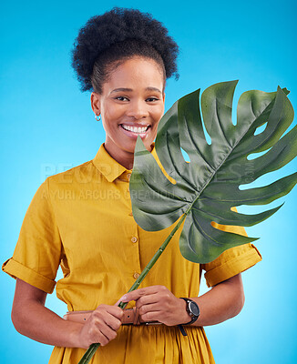 Buy stock photo Fashion, portrait and black woman with plant on blue background for eco friendly, organic and natural clothes. Nature, happy and female person with monstera leaf for sustainable clothing in studio