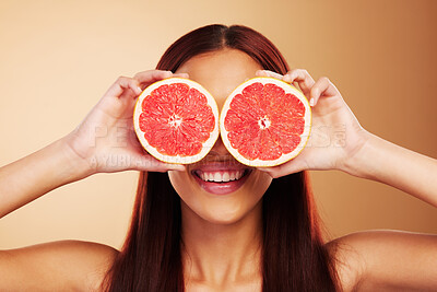 Buy stock photo Beauty, grapefruit and a woman with skin care in studio for natural dermatology, cosmetics or wellness. Facial, fruit and healthy diet for detox or nutrition of model person on a brown background 