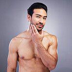 Portrait, skincare and man with muscle, cosmetics and dermatology against a grey studio background. Face, male person or model with self care, beard treatment or facial with wellness, shine or luxury