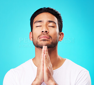 Praying, man and hands in meditation or worship to God for faith or belief in spirituality, mindfulness and peace in studio. Christian, prayer and person with religion and zen on blue background
