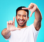 Happy, hand frame and portrait of a man for a selfie, creative aesthetic or advertising photography. Smile, laughing and face of an Asian person with a gesture for a photo on a blue background
