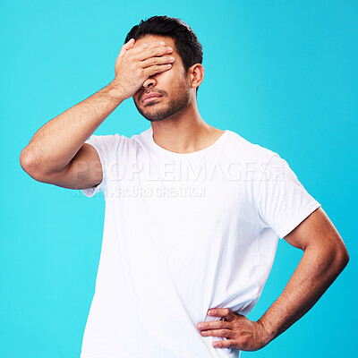 Man, face palm and mistake in studio with thinking, regret or anxiety for fail by blue background. Young guy, student and cover eyes with stress, memory and shame for bad decision with cotton t-shirt