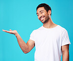 Mockup, showing and man with a smile, opportunity and decision against a blue studio background. Male person, advertising and model with product placement, hand gesture and presentation with sign