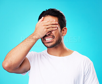 Buy stock photo Scared, covering eyes and a man on a blue background for fear, anxiety or angry with a problem. Mental health, fail and a person with hands on face while frustrated and isolated on a studio backdrop