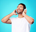 Music, headphones and happy man listening in studio isolated on a blue background. Radio, smile and person with audio, sound or hearing podcast, jazz or media for hip hop with eyes closed for freedom