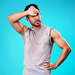 Portrait, fitness and Asian man tired after exercise in studio isolated on a blue background. Face, serious and athlete with fatigue, wipe sweat and workout for sports, healthy body and wellness