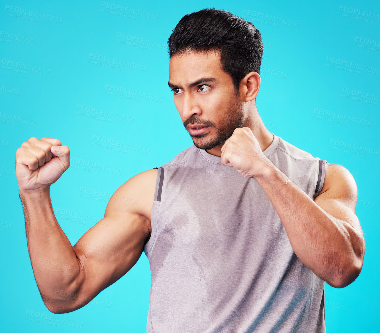 Buy stock photo Fitness, man and fighter training, sports and exercise against a blue studio background. Male person, sweating or serious athlete with power, strong or energy with workout goals, fight or competition
