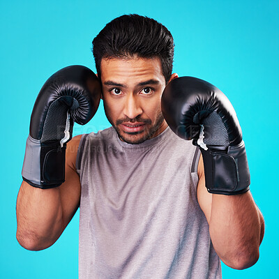 Buy stock photo Boxing, man and fighter training, portrait or challenge against a blue studio background. Male person, boxer or serious athlete with power, face or energy with workout goals, fight or strong champion