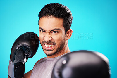 Buy stock photo Angry boxer man, studio portrait and punch for workout, training and fitness by blue background. Athlete, boxing gloves and power for exercise, fight and development for performance in combat sports