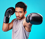 Portrait, man and training with boxing, punch and sports 
challenge against a blue studio background. Male person, competition and serious boxer with power, strong or energy with exercise or fighting