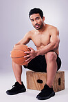Portrait, fitness and basketball with a man on a box in studio on a gray background for training or a game. Exercise, workout or mindset and a young male sports athlete holding a ball with focus