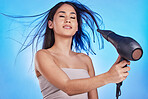 Hair care, hairdryer and beauty of a woman in studio for cosmetics, self care and heat tools. Salon, hairdresser and a female model person with a dryer for shampoo results on a blue background