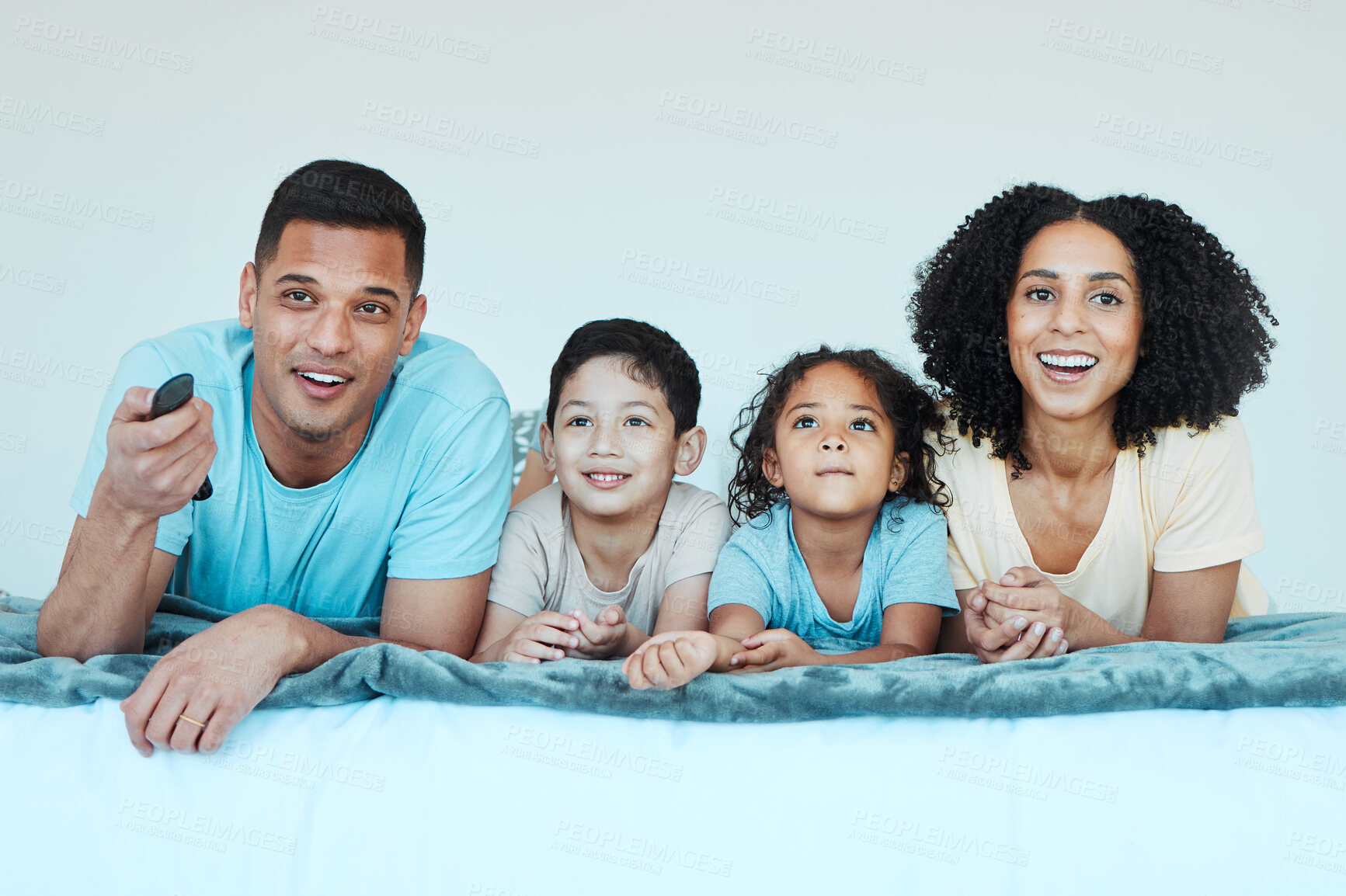 Buy stock photo Father, mother and children on bed, watching tv and smile for comedy, comic movie and cartoon in family home. Happy parents, kids and television show with streaming, subscription and relax together