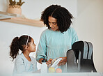 Mother packing lunch for her girl child for health, wellness snacks in the kitchen of their home. Happy, bonding and young mom talking and preparing food for her kid for school in their family house.