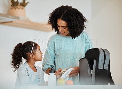 Buy stock photo Mother packing lunch for her girl child for health, wellness snacks in the kitchen of their home. Happy, bonding and young mom talking and preparing food for her kid for school in their family house.