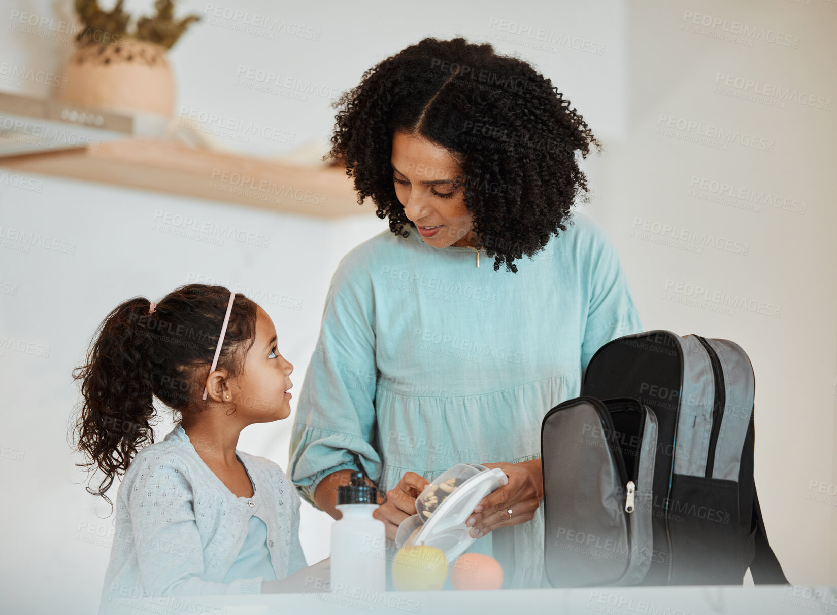 Buy stock photo Mother packing lunch for her girl child for health, wellness snacks in the kitchen of their home. Happy, bonding and young mom talking and preparing food for her kid for school in their family house.