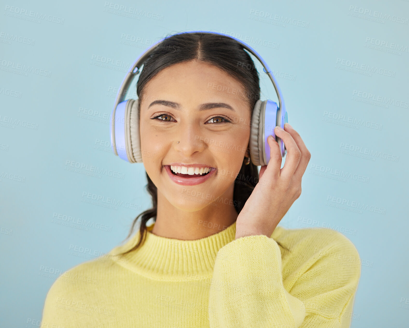 Buy stock photo Portrait of happy woman, headphones and mockup in studio listening to podcast, mobile app and streaming radio site. Smile, music media subscription and sound, face of girl on blue background space.