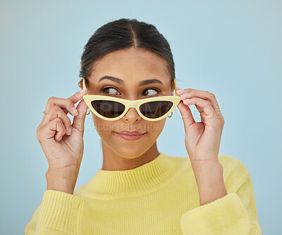 Buy stock photo Sunglasses, gen z and young woman in a studio with a casual, stylish and cool sweater outfit. Confident, face and female model with trendy style and fashion accessory isolated by a blue background.