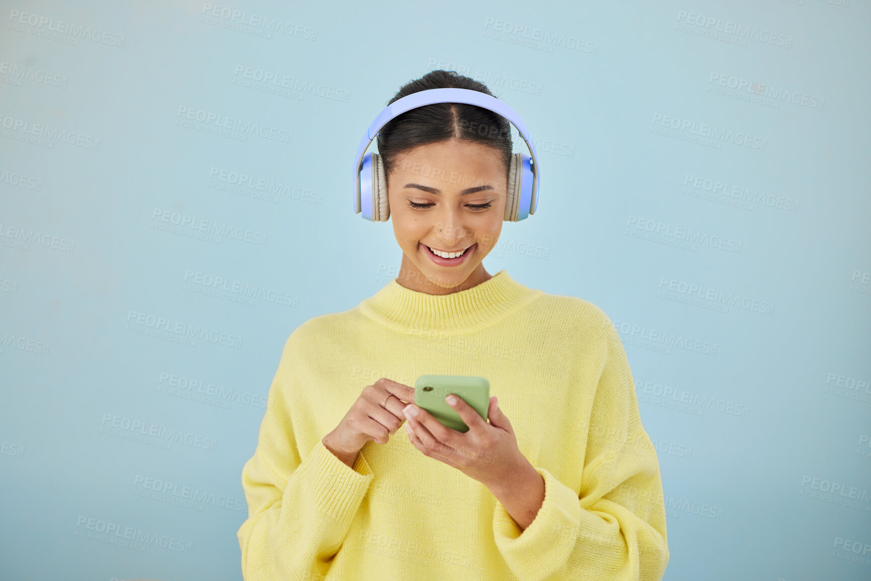 Buy stock photo Woman with phone, headphones and mockup in studio for social media post, mobile app and streaming radio site. Smile, music media subscription and happy girl with cellphone on blue background space.