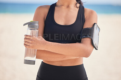 Buy stock photo Woman, fitness and water with arms crossed on beach for workout, exercise or natural outdoor nutrition. Hands of female person with bottle of mineral liquid for running, training or healthy wellness