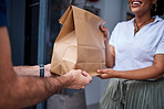 Delivery, customer and hands with a paper bag at door from courier man at home. Giving woman or a client a package, parcel or fast food from online shopping, e-commerce or distribution service