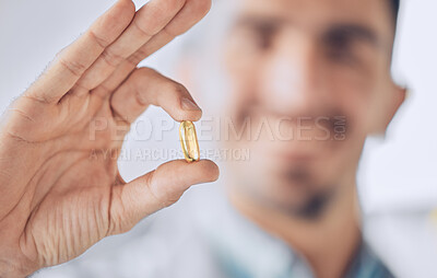 Man, hand of doctor and pill, pharmaceutical drugs and treatment of illness at hospital with blurred background. Healthcare, medicine and medical professional with gold capsule to help with health.