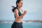 Running, exercise and woman at a beach for fitness, training and body performance workout on blurred background. Sports, wellness and female runner at the sea for resilience, challenge or ocean run