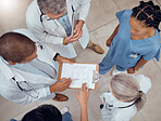 Group of doctors, nurses and checklist in hospital from above, meeting and planning surgery or schedule. Healthcare, discussion and medical staff with clipboard, info and talking together in clinic.